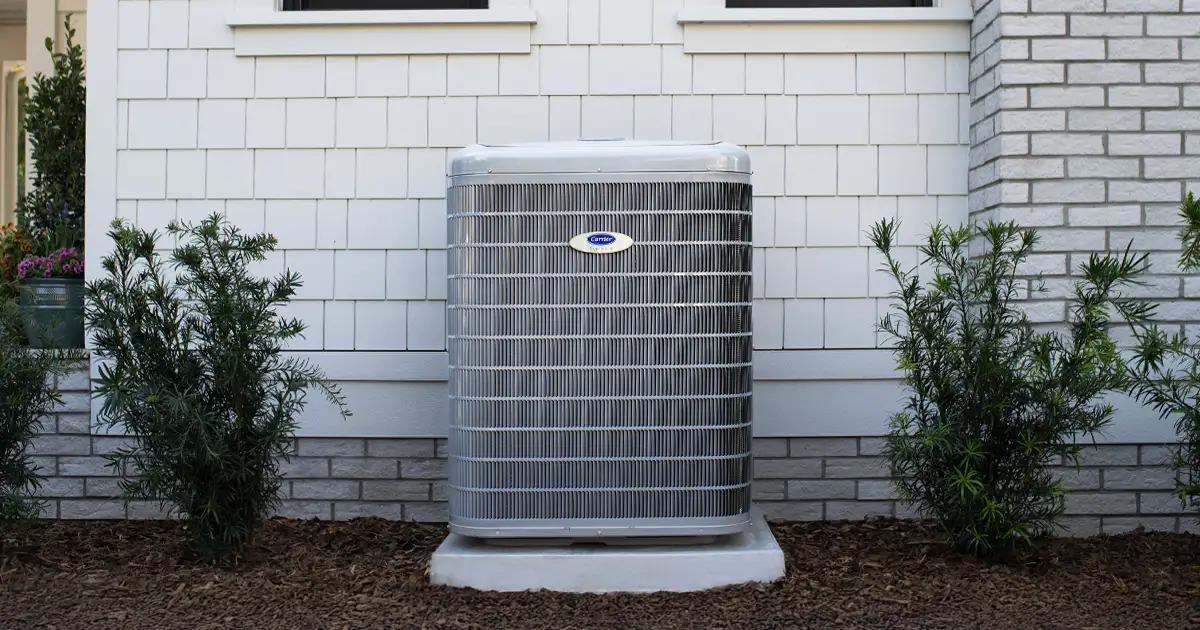 an outdoor AC unit against a white brick wall