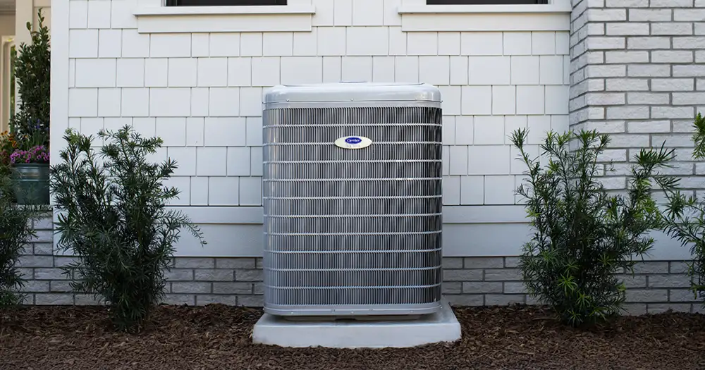 an outdoor AC unit against a white brick wall