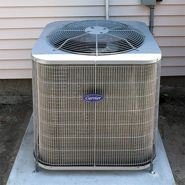 Outdoor Carrier central air conditioner unit cleanly installed on a concrete equipment pad next to residential siding.