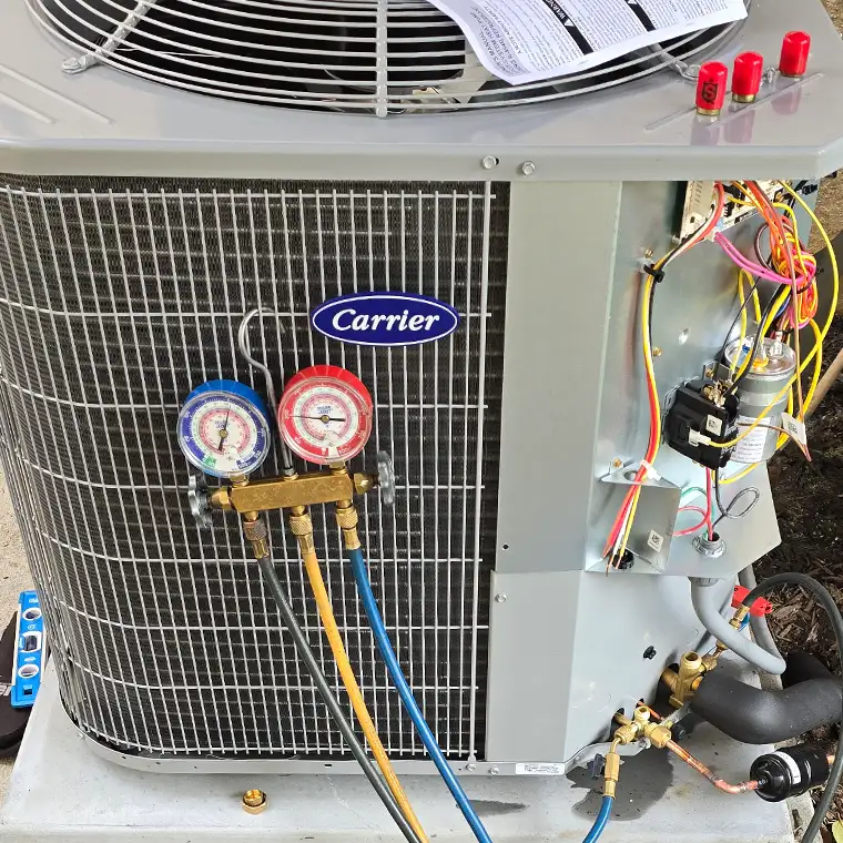 Pressure manifold gauges attached to a opened Carrier outdoor AC condenser unit showing exposed wiring during a system check.