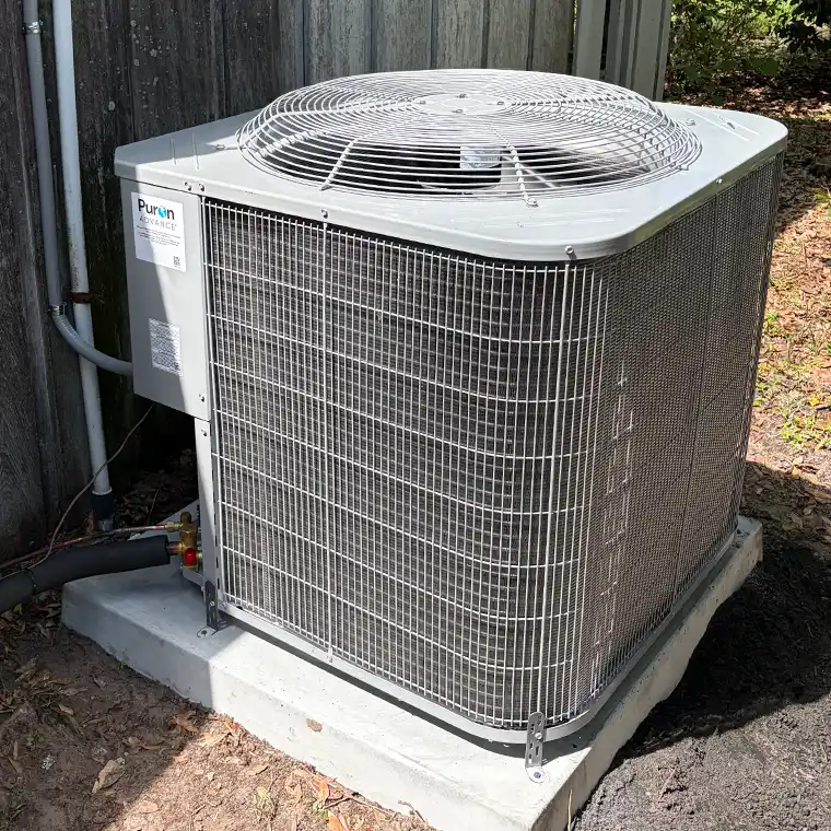 Freshly installed Carrier Puron central AC unit on a concrete pad next to a wooden fence.