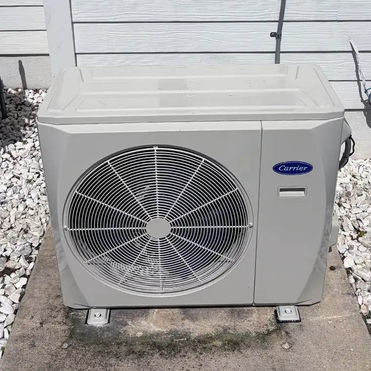 A side-discharge Carrier heat pump unit installed outdoors on concrete and gravel.
