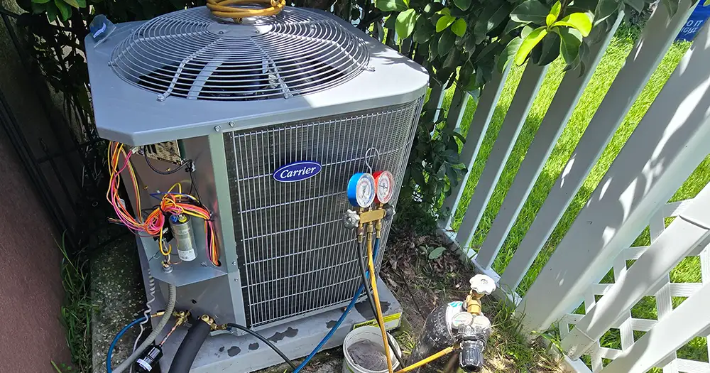 Carrier outdoor AC unit being serviced with refrigerant gauges during an AC repair in Orlando.