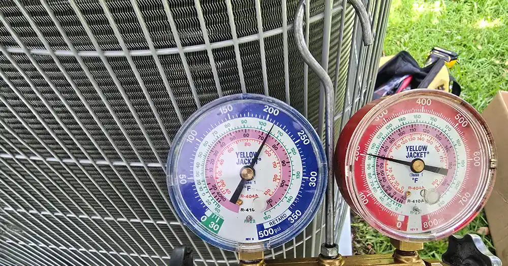 Refrigerant pressure gauges used to check an outdoor AC unit during maintenance in Jacksonville.